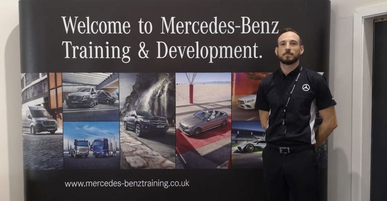 Mercedes trainer standing in front of Welcome to Mercedes-Benz Training and Development sign 