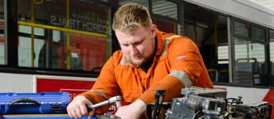 apprentice working on bus engine