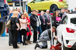 A group at a GTG open day watching and apprentice work on a car in the workshop