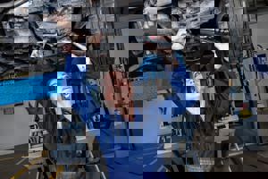 Female apprentice working underneath a car on the ramps