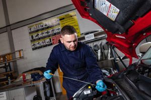 Apprentice checking the engine oil in a car