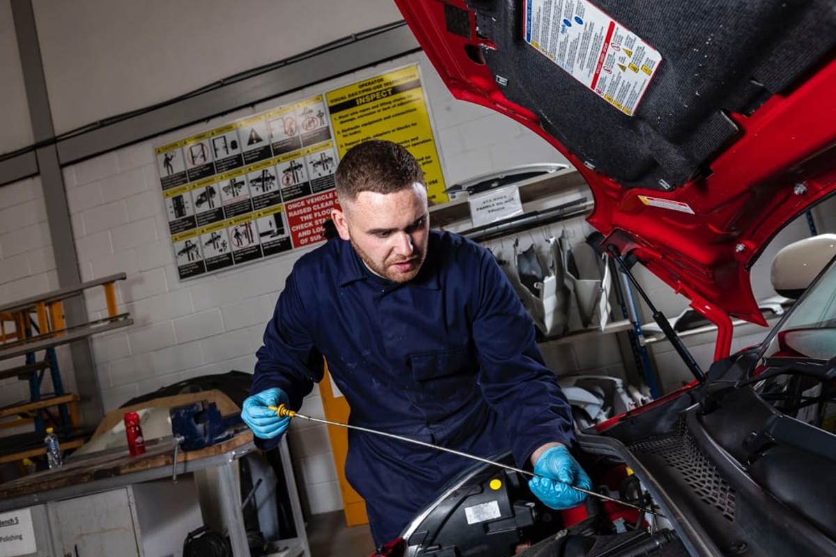 Apprentice checking the engine oil in a car